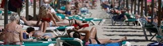 Mallorca: Menschen sonnen sich am Strand von Arenal. Palma de Mallorca will künftig die Reservierungen von Sonnenliegen am Strand mit einer App regeln.