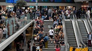 Reisende sitzen auf einer Treppe am Gare de Montparnasse vor den Olympischen Sommerspielen 2024. Wenige Stunden vor der Eröffnung der Olympischen Spiele in Paris haben Unbekannte Brandanschläge auf mehreren Anlagen des französischen Schnellzugnetzes verübt.
