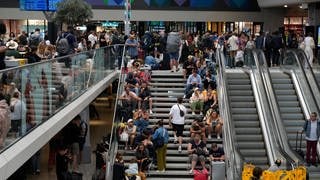 Nach den Angriffen auf das französische Bahnnetz: Hunderte Reisende sitzen auf einer Treppe am Gare de Montparnasse in Paris und kommen nicht weiter.