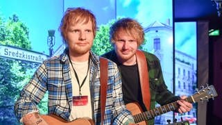 Ed Sheeran Double, steht neben der Wachsfigur des britischen Sängers Ed Sheeran im Wachfigurenkabinett Madame Tussauds Berlin. 