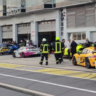 Feuerwehrleute laufen vor Box 27 in der Boxengasse des Nürburgrings. Bei der Explosion einer Druckluftflasche hinter der Box im Bereich des Fahrerlagers wurden etliche Menschen verletzt. Druckluft aus Flaschen wird unter anderem eingesetzt, um die Rennwagen schnell anzuheben, beispielsweise bei einem Boxenstopp zum Wechseln der Reifen. 