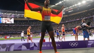 Leo Neugebauer hält eine Flagge von Deutschland hinter sich, nachdem er bei Olympia Silber gewonnen hat.