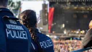 Polizisten beobachten Fans vor einer Bühne.