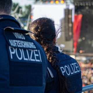 Polizisten beobachten Fans vor einer Bühne.