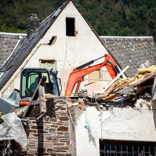 Ein Bagger reißt das eingestürzte Hotel in Kröv weiter ab.