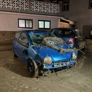 Hochwasserchaos Gondelsheim: Man sieht ein Auto das mit Schlick und Pflanzen vom Hochwasser überzogen ist.