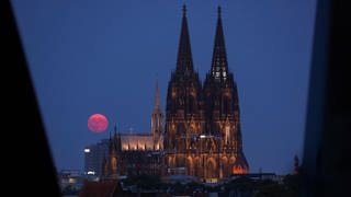 Genauso beeindruckend: Der Supermond leuchtet rot über dem Kölner Dom.