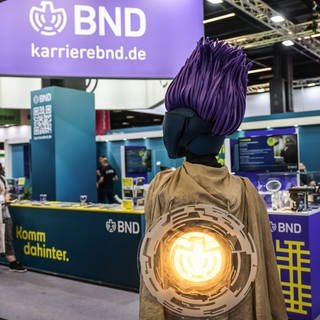 Cosplayerin „Operateurin AJ“ steht am Stand des BND und wartet auf Interessierte.