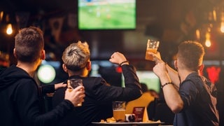 Drei Männer schauen in einer Bar Fußball. Die nächste Bundesliga-Saison beginnt jetzt mit einigen Neuerungen.