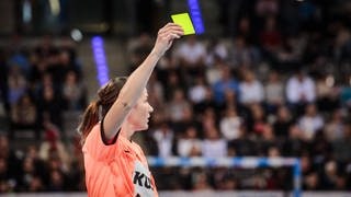 Eine Schiedsrichterin hält bei einem Handball-Spiel die Gelbe Karte nach oben