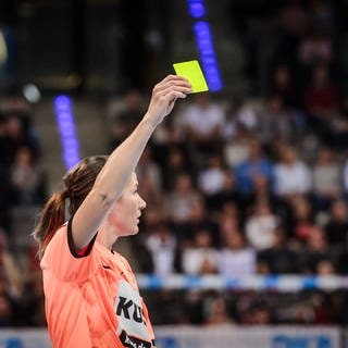 Eine Schiedsrichterin hält bei einem Handball-Spiel die Gelbe Karte nach oben