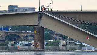 Menschen stehen an der Stelle, hinter der die auf Carolabrücke in Dresden eingestürzt ist.