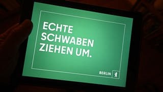 Der Werbeslogan „Echte Schwaben ziehen um“ einer Berliner Image Kampagne von der Agentur DOJO für Partner für Berlin GmbH  Senatskanzlei Berlin ist auf einem Tablett Bilschirm dargestellt. Baden-Württemberger werden mit dem Slogan auf Plakaten zum Umzug in die Hauptstadt aufgefordert.