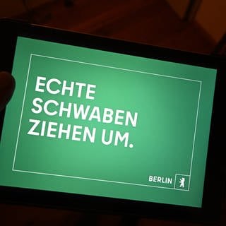 Der Werbeslogan „Echte Schwaben ziehen um“ einer Berliner Image Kampagne von der Agentur DOJO für Partner für Berlin GmbH  Senatskanzlei Berlin ist auf einem Tablett Bilschirm dargestellt. Baden-Württemberger werden mit dem Slogan auf Plakaten zum Umzug in die Hauptstadt aufgefordert.