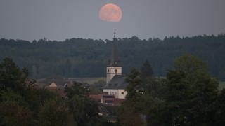 Der „Supermond“ geht hinter der Kirche von Wehrheim im hessischen Taunus auf.