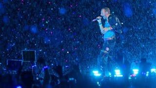 Chris Martin, Sänger der britischen Band Coldplay steht bei einem Konzert im Rahmen der „Music of the Spheres Tour 2024“ bei strömendem Regen auf der Bühne. 