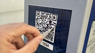 Ein QR-Code klebt über einem anderen an einer Parkuhr in Basel.