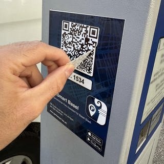 Ein QR-Code klebt über einem anderen an einer Parkuhr in Basel.