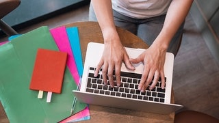 Eine Frau tippt auf ihrem Laptop.