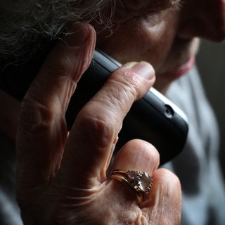 Eine ältere Frau telefoniert mit einem schnurlosen Festnetztelefon. Viele ältere Menschen fallen immer wieder auf Trickbetrüger herein.