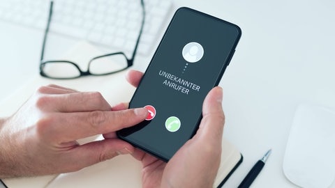 Ein Mann drückt auf einem Smartphone, auf dem ein unbekannter Anrufer anruft, auf den Auflegen-Button.