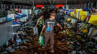 Menschen sammeln beschädigte Waren in einem von den Überschwemmungen betroffenen Supermarkt ein.