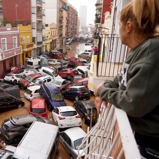 Eine Frau blickt von ihrem Balkon aus auf Fahrzeuge, die nach Überschwemmungen auf der Straße stecken geblieben sind. Szene nach den verherenden Überlfutungen in Spanien, wo besonders die Region um die Stadt Valencia betroffen war.