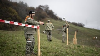 Zivilschützer sperren die Gefahrenzone rund um Brienz mit Flatterbändern und Pfosten ab.