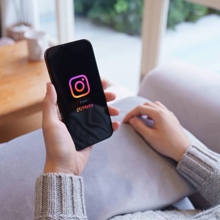 Instagram von Meta lädt auf einem Handy, das jemand in der Hand hält.
