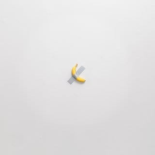 Eine Banane klebt mit Klebeband an der Wand, ein Kunstwerk von Maurizio Cattelan.