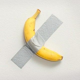 Eine Banane klebt mit Klebeband an der Wand, ein Kunstwerk von Maurizio Cattelan.