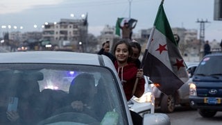 Damaskus am Sonntagnachmittag: Ein kleines Mädchen sitzt lächelnd in einem Autofenster und hält eine syrische Fahne.