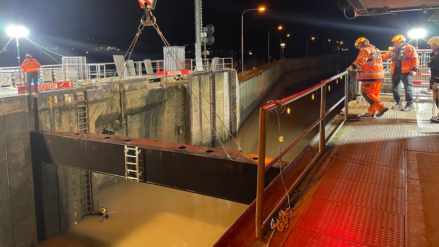 Arbeiter stehen an der provisorischen Mosel-Schleuse, ein Taucher schwimmt im Wasser