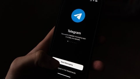 Jemand hält ein Smartphone in der Hand, auf dem die Telegram-App geöffnet ist