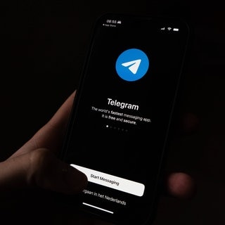 Jemand hält ein Smartphone in der Hand, auf dem die Telegram-App geöffnet ist