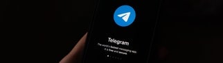 Jemand hält ein Smartphone in der Hand, auf dem die Telegram-App geöffnet ist