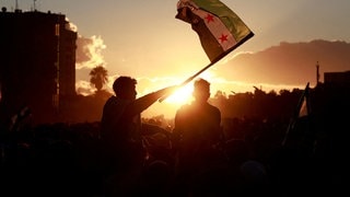 Mann schwenkt eine syrische Flagge: Nach dem Sturz von Assad gab es die erste Demonstration in Damaskus für Demokratie und Freiheit