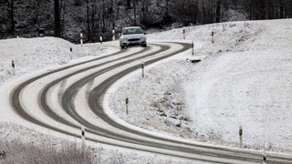 Auto auf schneebedeckter Straße: Beim Reiseverkehr an Weihnachten muss in Höhenlagen auf Glatteis und Schneefall geachtet werden