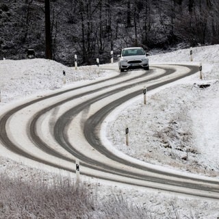 Auto auf schneebedeckter Straße: Beim Reiseverkehr an Weihnachten muss in Höhenlagen auf Glatteis und Schneefall geachtet werden