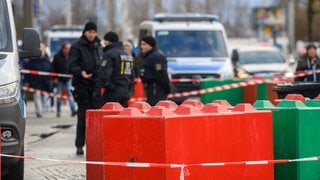 Polizisten stehen hinter Betonklötzen am Rande des Weihnachtsmarkts in Magdeburg