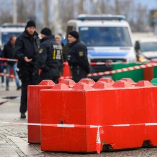 Polizisten stehen hinter Betonklötzen am Rande des Weihnachtsmarkts in Magdeburg