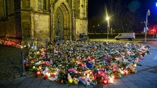 Zahlreiche Blumen, Kuscheltiere und Kerzen liegen vor der Johanniskirche in Magdeburg zum Gedenken an die Opfer des Anschlags.