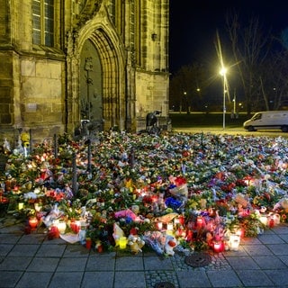 Zahlreiche Blumen, Kuscheltiere und Kerzen liegen vor der Johanniskirche in Magdeburg zum Gedenken an die Opfer des Anschlags.