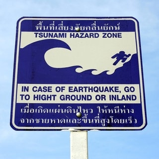 Ein Schild, das auf Englisch und Thai vor Tsunamis warnt