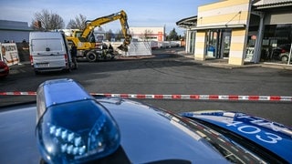 Ein Bagger steht nach einer Zerstörungsfahrt neben einem Autohaus in Tauberbischofsheim.