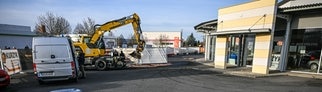 Ein Bagger steht nach einer Zerstörungsfahrt neben einem Autohaus in Tauberbischofsheim.