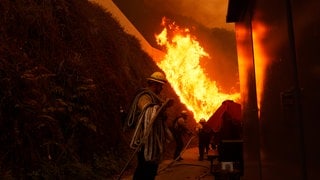 Feuerwehrleute schützen Gebäude vor dem sich ausbreitenden Palisades-Feuer im Stadtteil Pacific Palisades von Los Angeles.