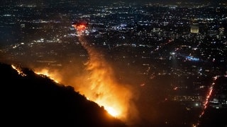 Ein Hubschrauber wirft Wasser auf das brennende Sunset Fire in den Hollywood Hills.