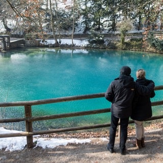 Zwei Besucher schauen auf den Blautopf. Jetzt ist er trotz Baustelle wieder täglich zugänglich.