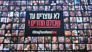 Bilder der von der Hamas entführten israelischen Geiseln sind an einer Mauer zu sehen mit dem Spruch „#BringThemHomeNow“